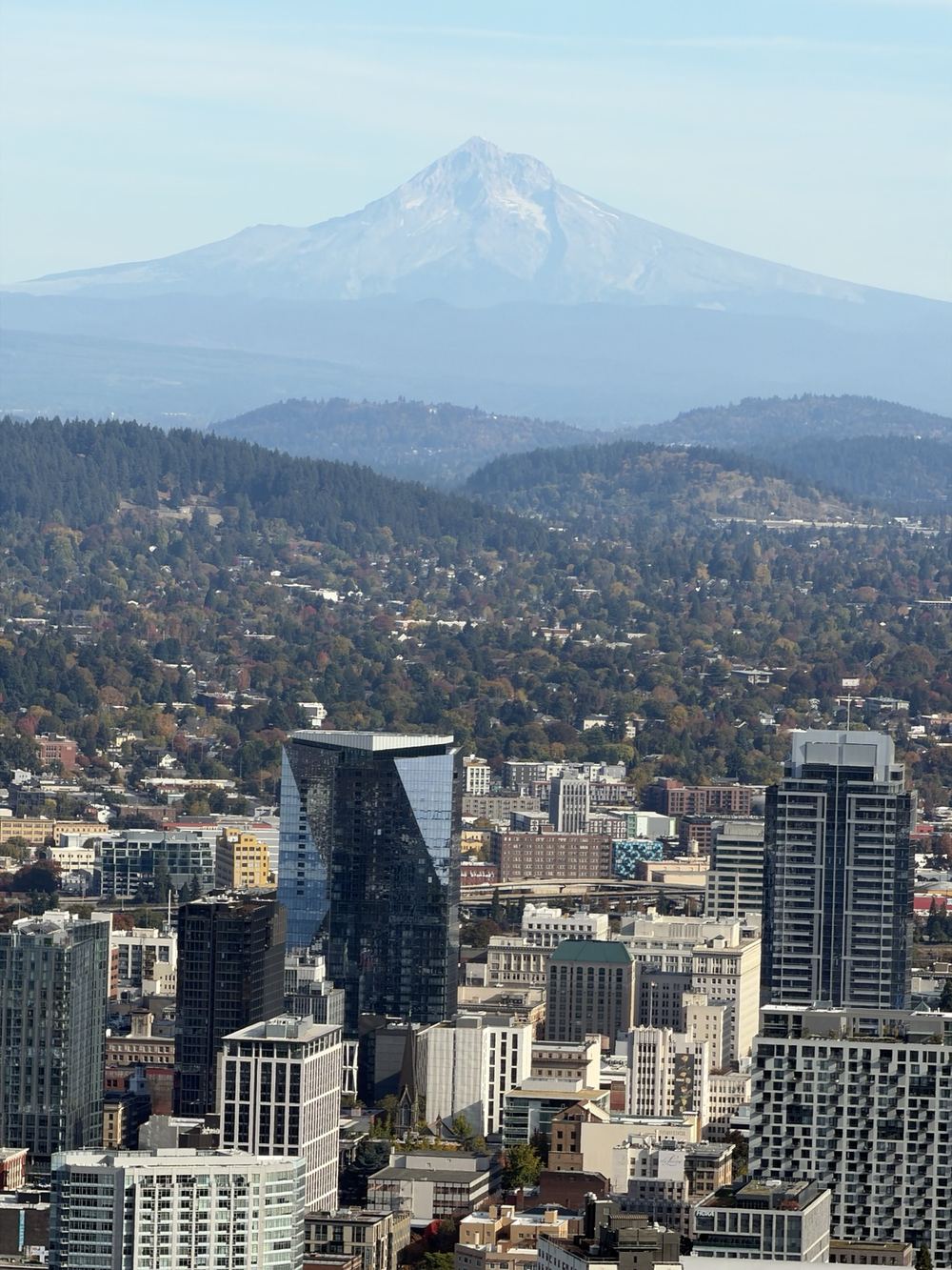 Mount Hood rising above downtown Portland under a pale blue sky